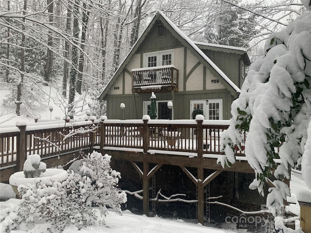 snow covered back of property featuring a wooden deck and a balcony