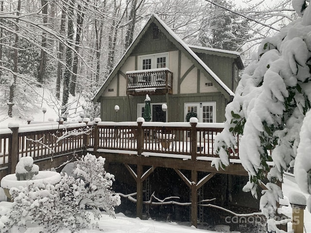 snow covered back of property featuring a deck and a balcony