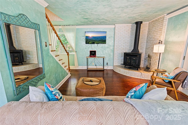 living area with baseboards, a wood stove, stairs, and hardwood / wood-style flooring