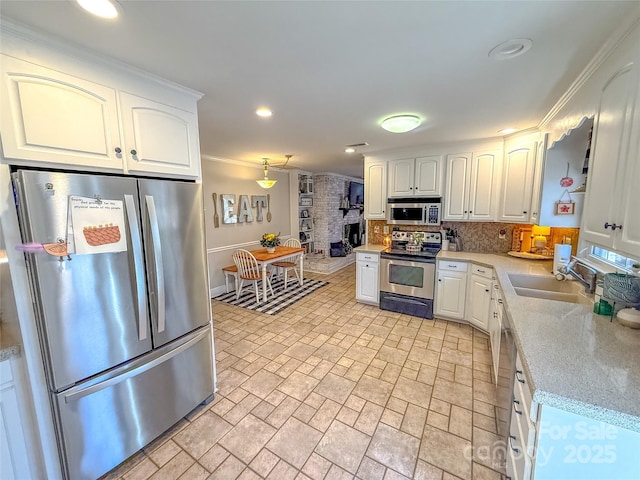 kitchen with hanging light fixtures, backsplash, appliances with stainless steel finishes, white cabinets, and a sink