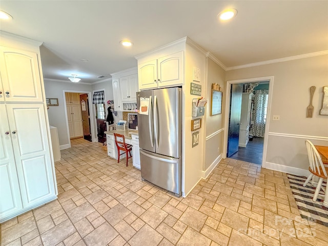 kitchen featuring freestanding refrigerator, white cabinets, crown molding, and baseboards