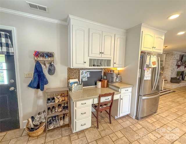 kitchen featuring freestanding refrigerator, light countertops, and white cabinetry