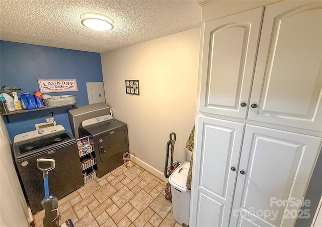 clothes washing area with stone finish flooring, a textured ceiling, laundry area, independent washer and dryer, and baseboards