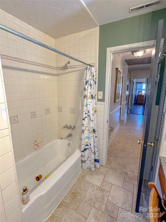 bathroom featuring shower / bath combo, stone tile flooring, visible vents, and tile walls