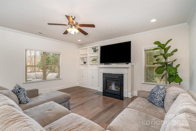 living room with ornamental molding, dark wood-type flooring, and ceiling fan