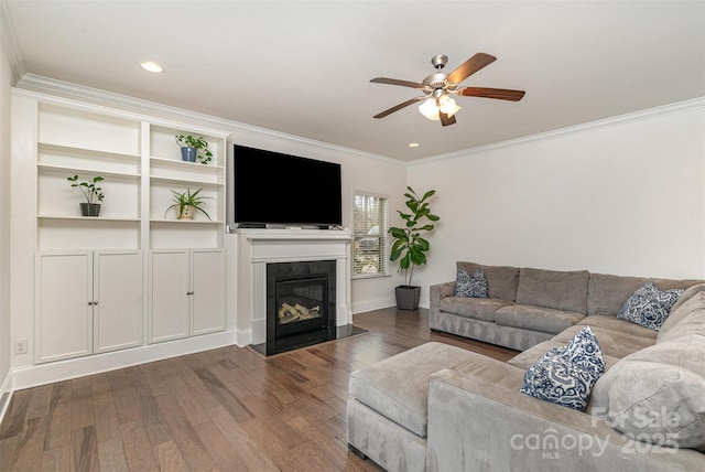 living room with dark hardwood / wood-style flooring, crown molding, a high end fireplace, and ceiling fan