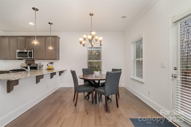 dining space with hardwood / wood-style flooring, ornamental molding, and a chandelier