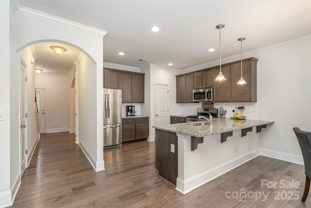 kitchen with light stone counters, decorative light fixtures, a kitchen breakfast bar, kitchen peninsula, and stainless steel appliances