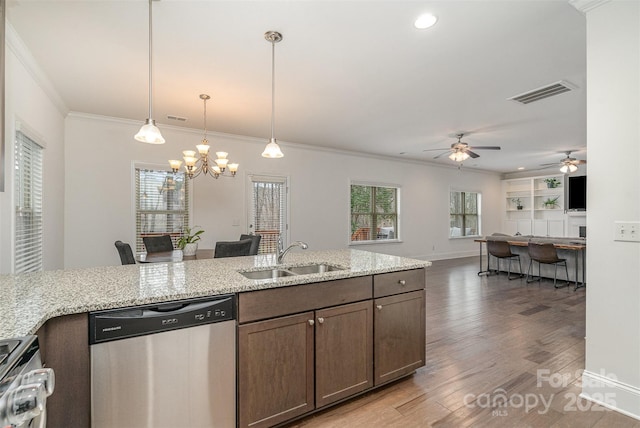 kitchen featuring appliances with stainless steel finishes, decorative light fixtures, wood-type flooring, sink, and light stone counters