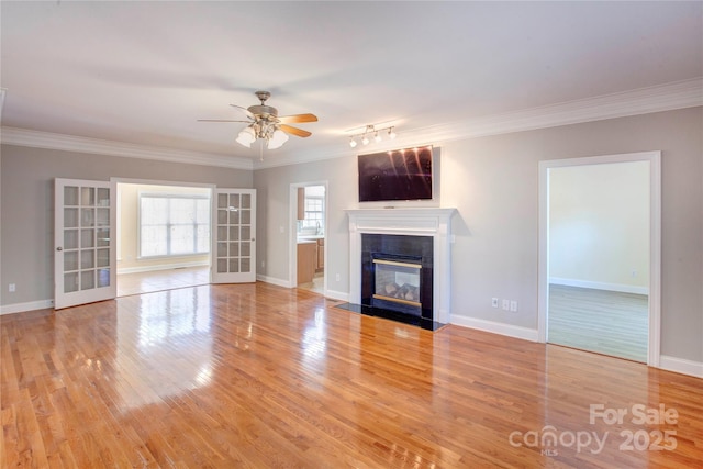 unfurnished living room featuring ceiling fan, crown molding, and light wood-type flooring