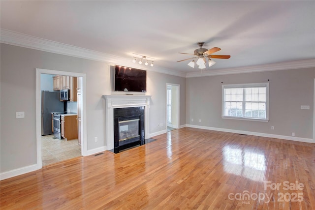 unfurnished living room featuring ceiling fan, ornamental molding, and light hardwood / wood-style floors