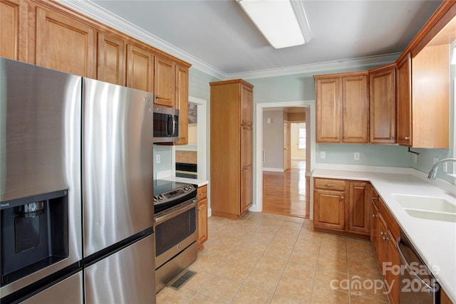 kitchen featuring sink, crown molding, light tile patterned floors, and appliances with stainless steel finishes