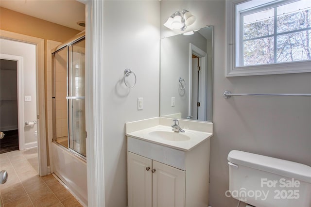 full bathroom featuring vanity, toilet, combined bath / shower with glass door, and tile patterned floors