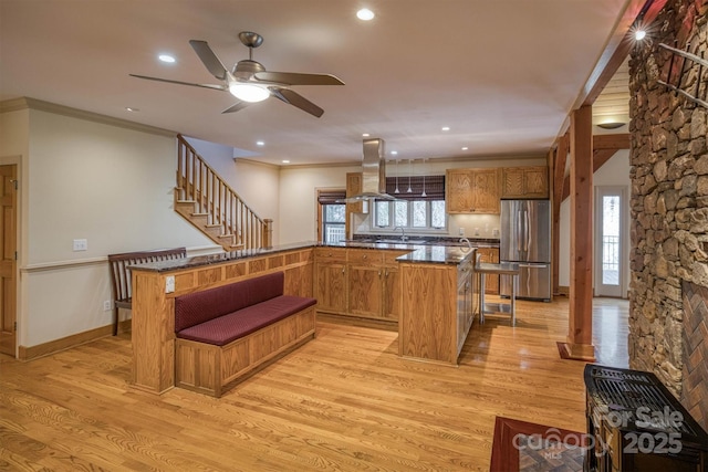 kitchen featuring island range hood, light hardwood / wood-style flooring, stainless steel fridge, and ornamental molding