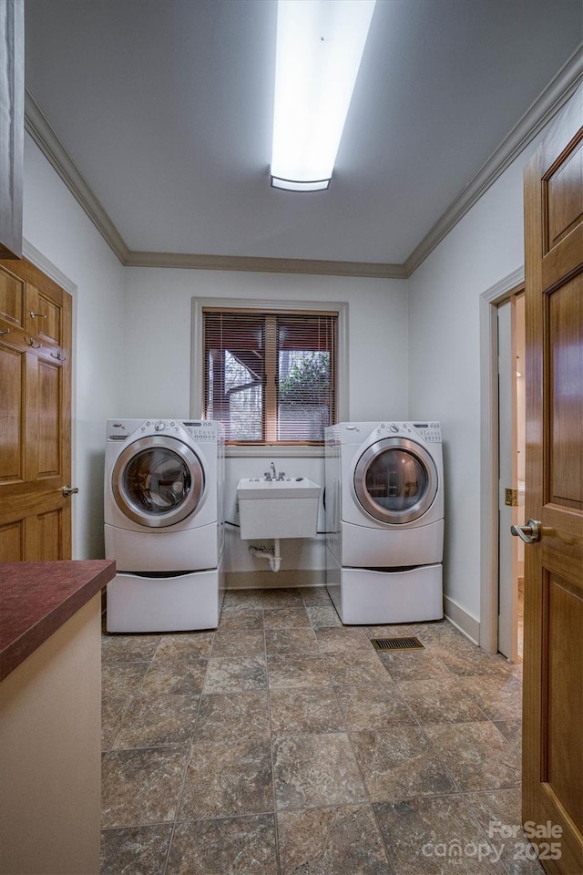 laundry area featuring sink, ornamental molding, and washer and dryer