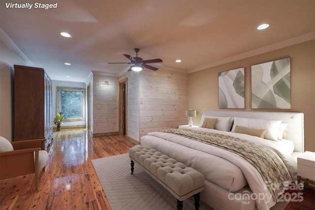 bedroom featuring ceiling fan, hardwood / wood-style floors, crown molding, and wooden walls