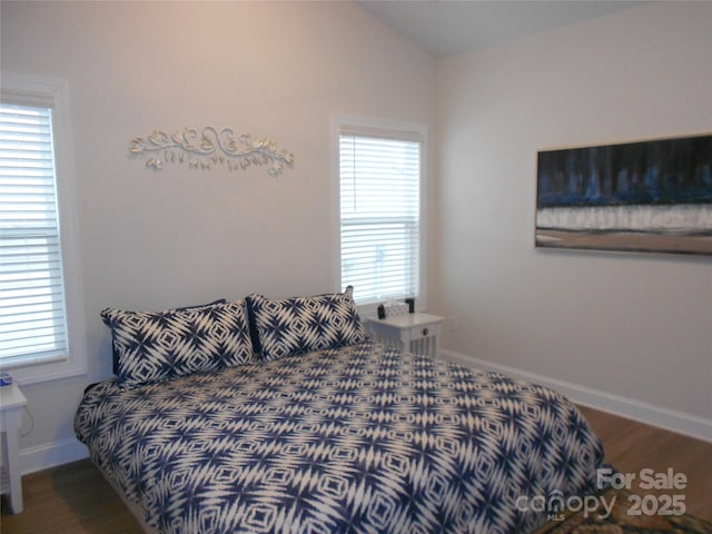 bedroom with lofted ceiling, baseboards, and wood finished floors