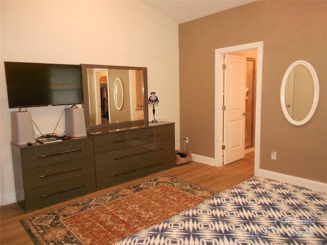 bedroom with vaulted ceiling, wood finished floors, and baseboards