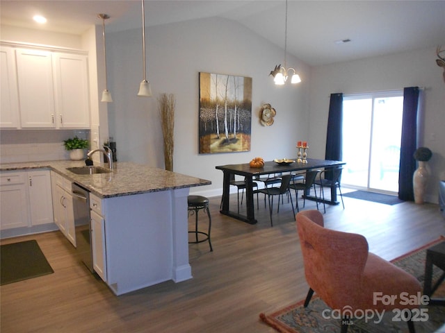 kitchen featuring wood finished floors, a sink, light stone countertops, white cabinetry, and a notable chandelier