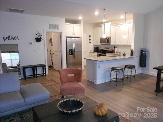 kitchen with stainless steel appliances, visible vents, a peninsula, and white cabinetry