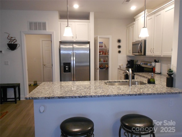 kitchen featuring tasteful backsplash, visible vents, stainless steel appliances, white cabinetry, and a sink