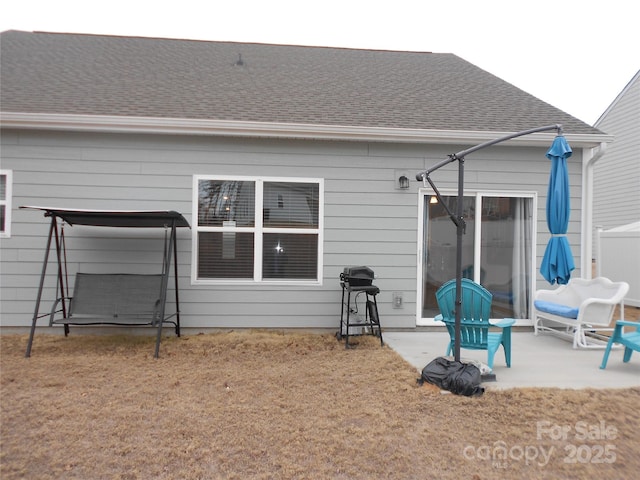 rear view of property with a shingled roof and a patio area