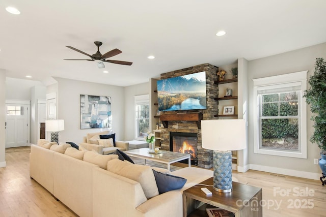 living room featuring ceiling fan, a fireplace, and light hardwood / wood-style flooring