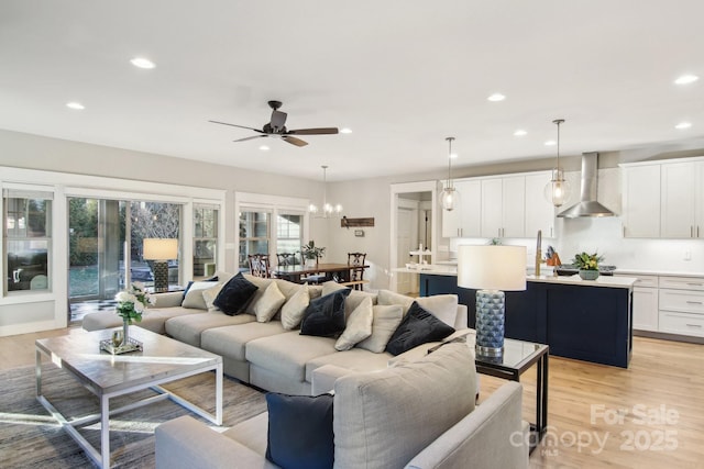 living room featuring ceiling fan, sink, and light wood-type flooring