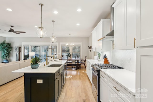 kitchen with sink, white cabinetry, appliances with stainless steel finishes, pendant lighting, and a kitchen island with sink