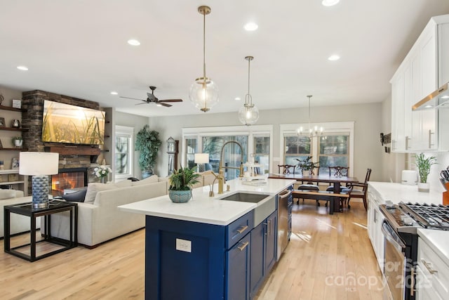 kitchen with decorative light fixtures, a stone fireplace, white cabinets, and blue cabinets