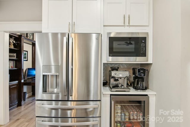 interior space with built in microwave, tasteful backsplash, stainless steel fridge, beverage cooler, and white cabinets