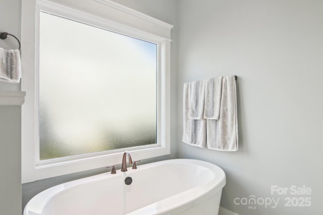 bathroom featuring a wealth of natural light and a tub to relax in