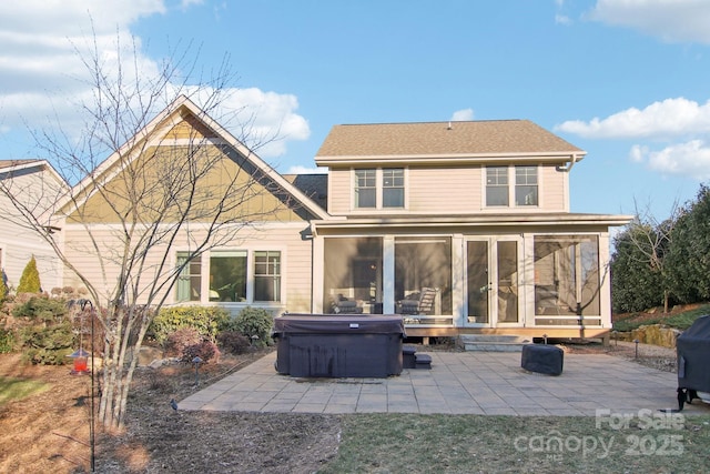 rear view of property featuring a patio area, a sunroom, and a hot tub