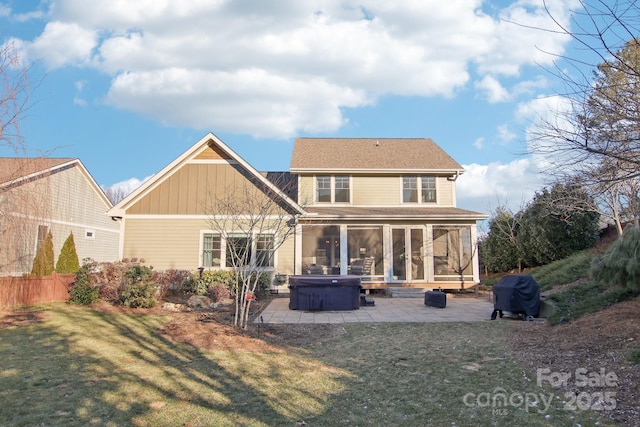 rear view of property with a hot tub, a sunroom, a lawn, and a patio area