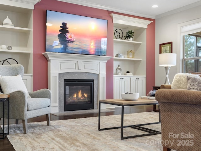 sitting room with built in shelves, ornamental molding, and hardwood / wood-style flooring