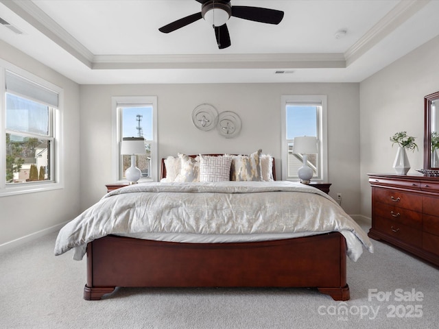 carpeted bedroom with a raised ceiling, ornamental molding, and multiple windows