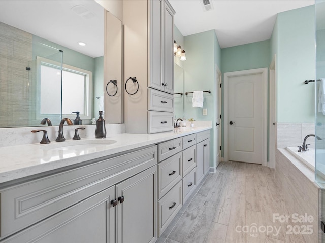 bathroom with hardwood / wood-style flooring, vanity, and plus walk in shower