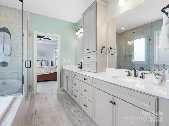 bathroom featuring ceiling fan, vanity, a shower with door, and wood-type flooring