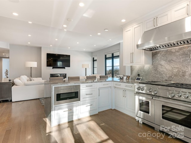 kitchen featuring range with two ovens, white cabinetry, backsplash, and kitchen peninsula