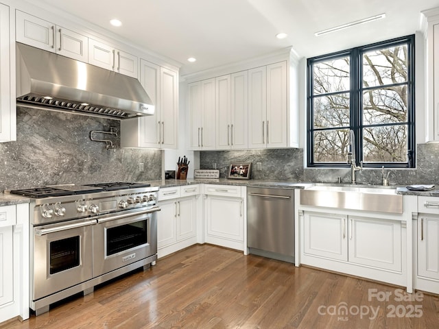 kitchen with sink, appliances with stainless steel finishes, backsplash, dark hardwood / wood-style floors, and white cabinets