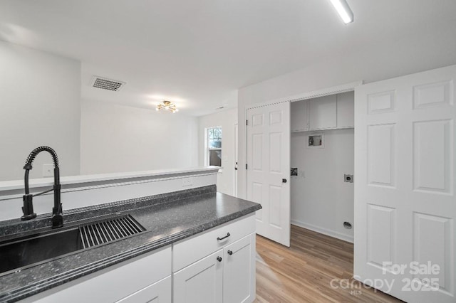 kitchen featuring sink, white cabinetry, and light hardwood / wood-style flooring