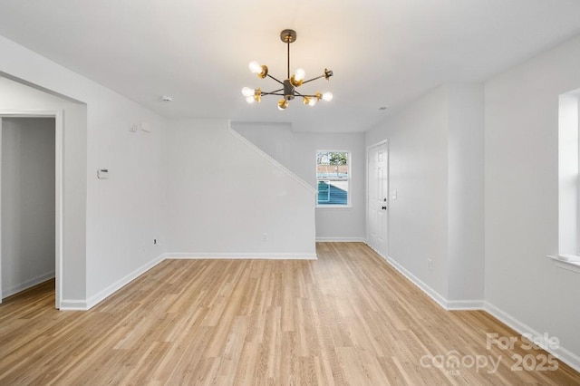 spare room featuring a chandelier and light wood-type flooring