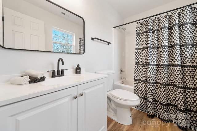 full bathroom with wood-type flooring, toilet, shower / bathtub combination with curtain, and vanity