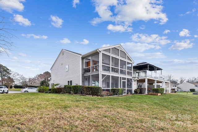 rear view of property with a lawn and a sunroom