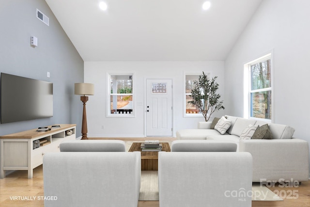 living room with vaulted ceiling, a healthy amount of sunlight, and light hardwood / wood-style flooring