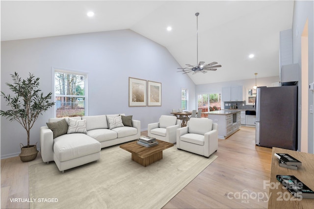 living room featuring light hardwood / wood-style flooring, high vaulted ceiling, and ceiling fan