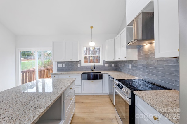 kitchen with appliances with stainless steel finishes, wall chimney exhaust hood, white cabinetry, sink, and hanging light fixtures