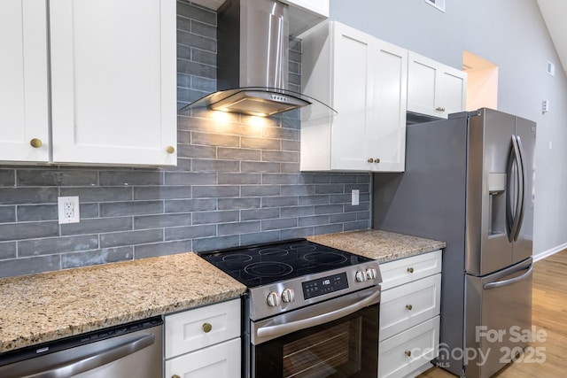 kitchen featuring backsplash, white cabinets, wall chimney range hood, and appliances with stainless steel finishes