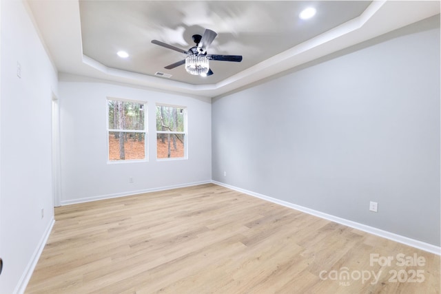 spare room featuring ceiling fan, light hardwood / wood-style flooring, and a raised ceiling