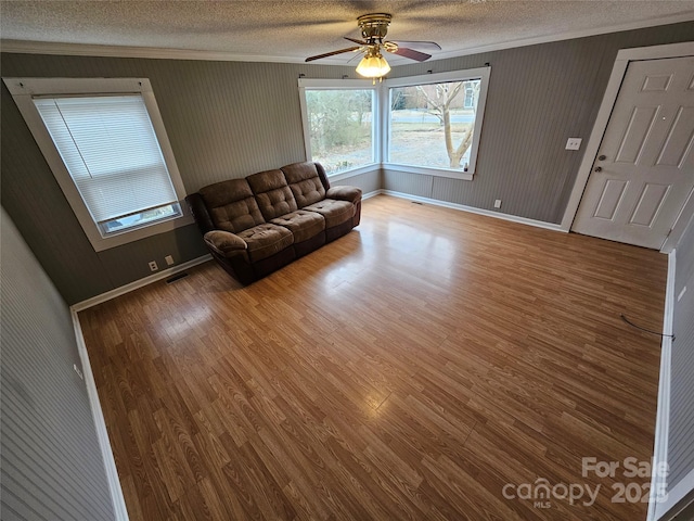 unfurnished living room featuring ceiling fan, crown molding, a textured ceiling, and wood-type flooring